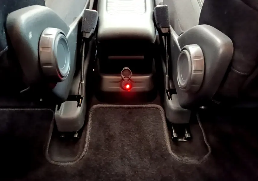 Vue rapprochée du plancher plat entre les sièges individuels arrière du Citroën Grand C4 SpaceTourer, avec prise allume-cigare rouge allumée.