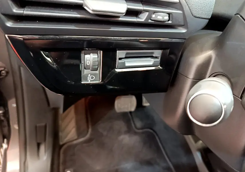 Détail du tableau de bord côté gauche du Citroën Grand C4 Spacetourer gris foncé avec réglage des phares et pédales visibles.