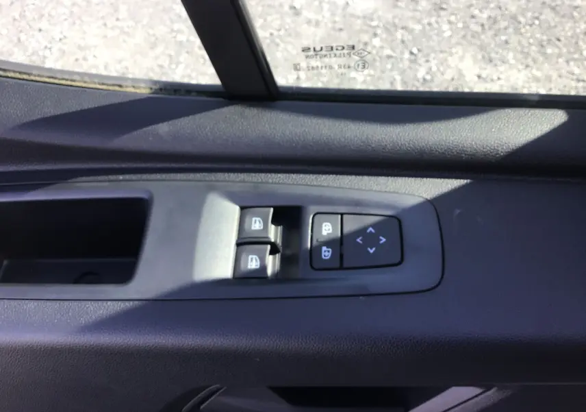Gros plan sur les commandes de lève-vitres et réglage des rétroviseurs côté conducteur du Renault Master blanc 2025.