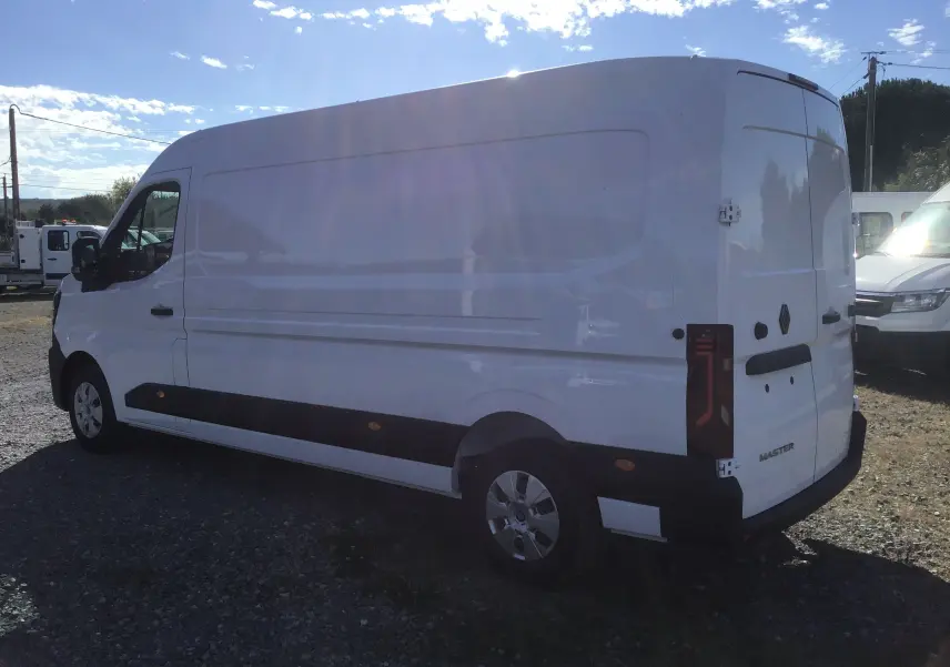 Renault Master blanc vu en 3/4 arrière côté gauche, montrant sa grande carrosserie utilitaire et ses feux arrière verticaux.
