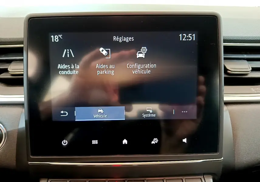Écran tactile central du tableau de bord du Renault Captur Business noir, affichant les réglages d’aides à la conduite et parking.