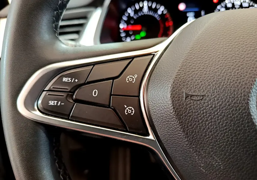 Gros plan sur les commandes du régulateur de vitesse au volant noir du Renault Captur Business Blue dCi 95 2020.