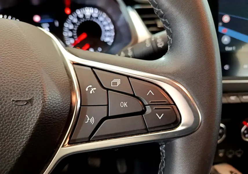 Gros plan sur les commandes au volant noir du Renault Captur 2020, avec tableau de bord et écran tactile en arrière-plan.