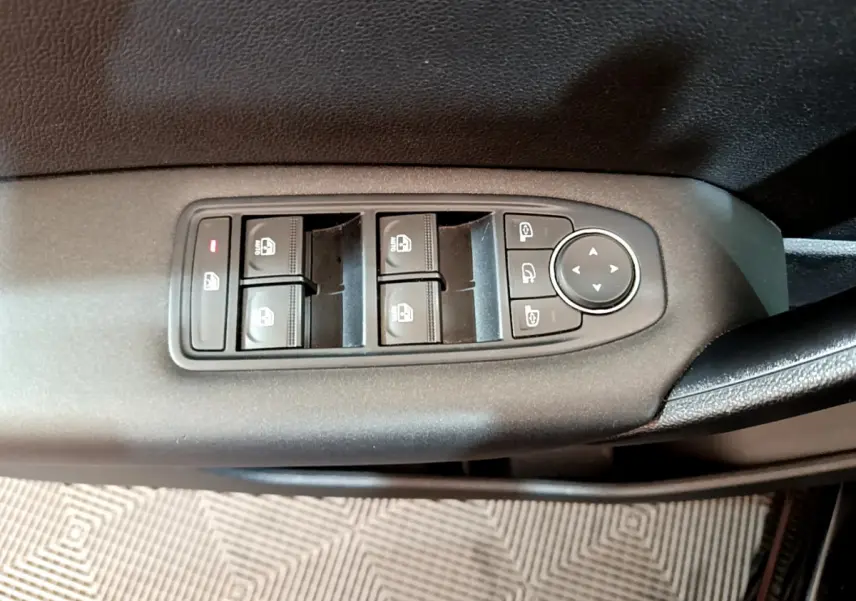 Vue rapprochée des commandes de lève-vitres et rétroviseurs sur la porte intérieure côté conducteur d’un Renault Captur noir.