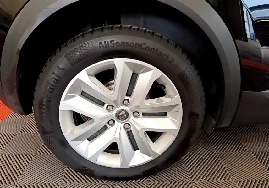 Gros plan sur la roue avant droite du Renault Captur noir, mettant en valeur la jante argentée et le pneu Continental AllSeasonContact.