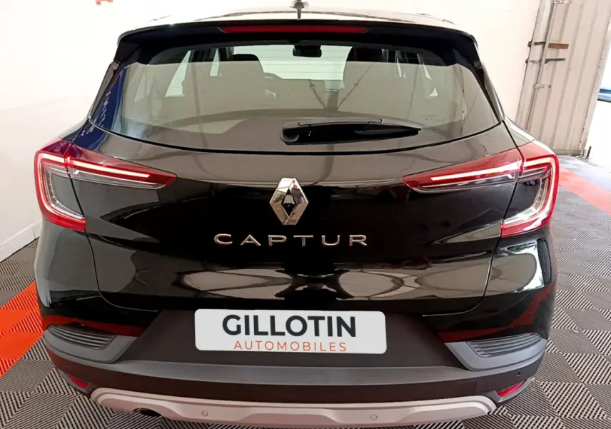 Vue arrière d'un Renault Captur noir avec feux LED allumés et logo central visible dans un garage.