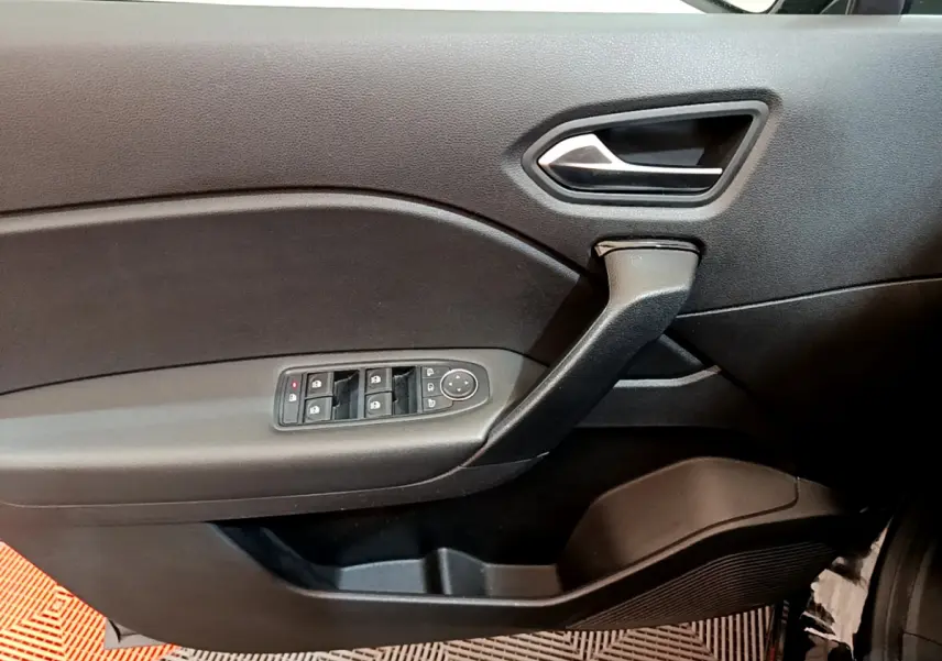 Vue intérieure du panneau de porte côté conducteur noir du Renault Captur Business Blue dCi 95 avec commandes de vitres et rétroviseurs.