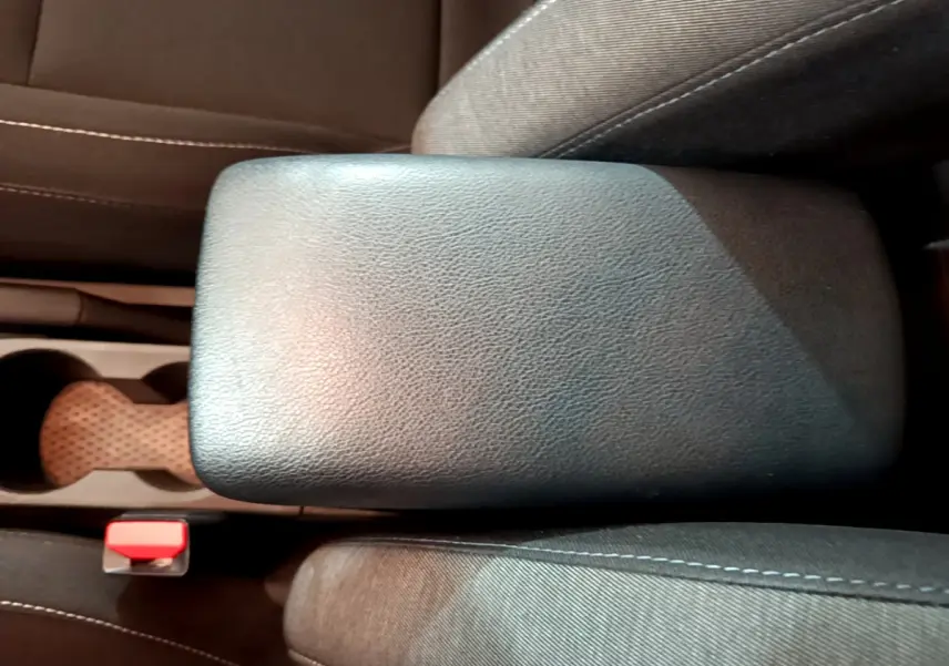 Vue rapprochée de l'accoudoir central noir et des sièges tissu gris du Renault Captur Business 2020.