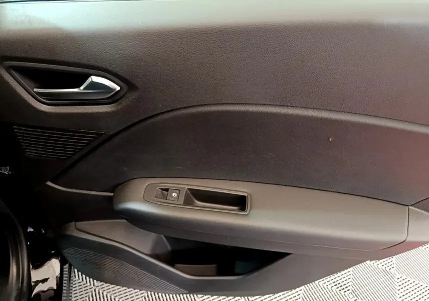 Vue intérieure du panneau de porte côté conducteur du Renault Captur noir, avec poignée argentée et commande de fenêtre.