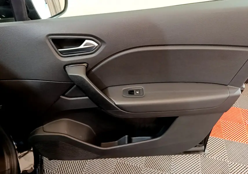 Vue rapprochée de la porte intérieure côté gauche noire du Renault Captur Business Blue dCi 95 avec poignée et commande de vitre.