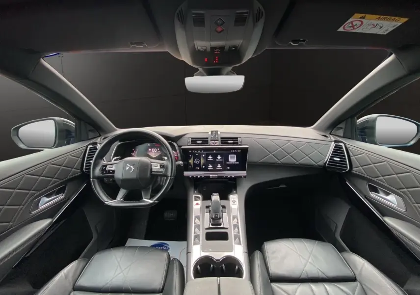 Vue intérieure avant du DS7 2024 avec sellerie cuir noir électrique et tableau de bord matelassé élégant.