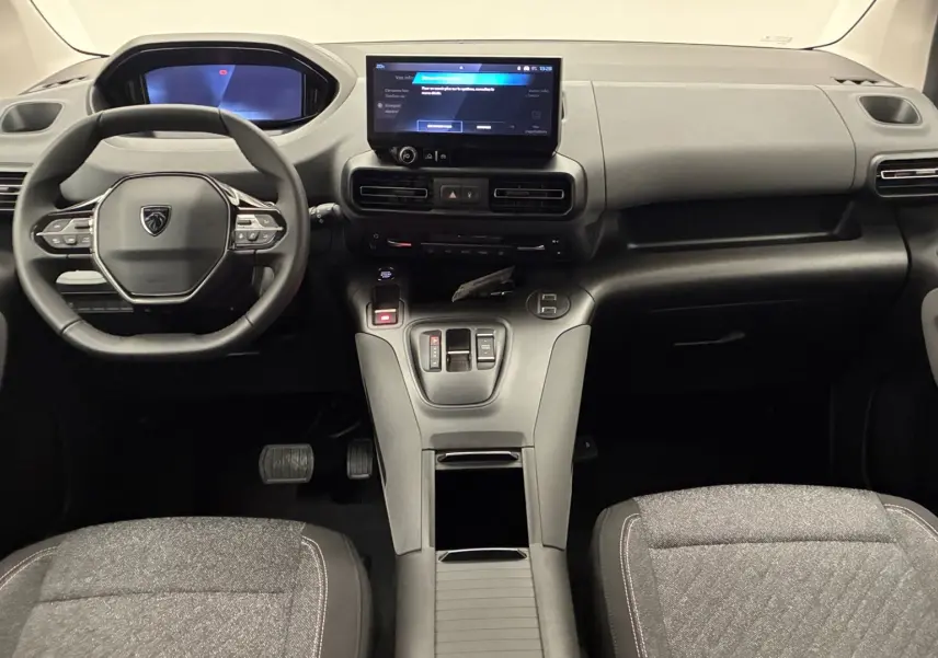 Vue intérieure avant du Peugeot Rifter 2026, tableau de bord noir avec écran tactile central et volant multifonction.