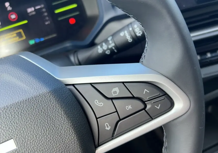 Gros plan sur le volant cuir à commandes multifonctions du Dacia Bigster Hybrid 155 Expression Plus, intérieur moderne.