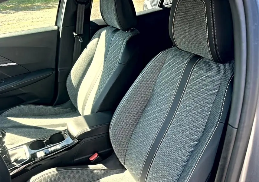 Vue intérieure rapprochée des sièges avant en tissu gris embossé de la Peugeot 2008 1.2 100 Allure 2025.