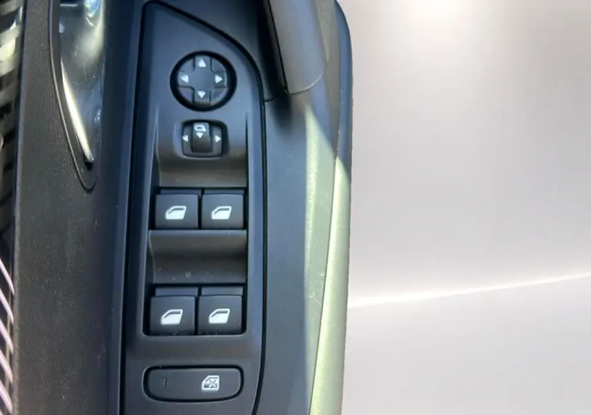 Détail des commandes des vitres et rétroviseurs côté conducteur de la Peugeot 2008 gris Artense, intérieur noir.