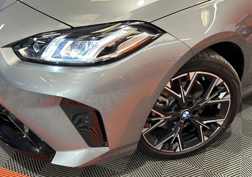 Gros plan sur l'avant droit d'une BMW Série 1 gris Skyscrap, mettant en valeur le phare LED et la jante alliage noire.