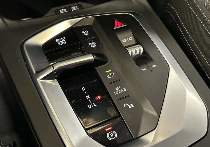 Gros plan sur la console centrale de la BMW Série 1 120DA 2024 avec levier de vitesse automatique et commandes multimédia.