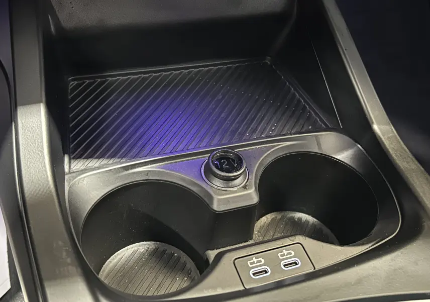 Gros plan sur la console centrale de la BMW Série 1 120DA 2024, montrant les porte-gobelets et deux ports USB.