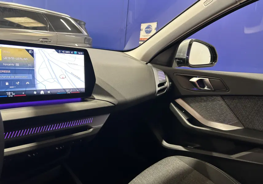 Intérieur moderne de BMW Série 1 120DA 2024, vue côté passager avec écran tactile et éclairage d'ambiance violet.