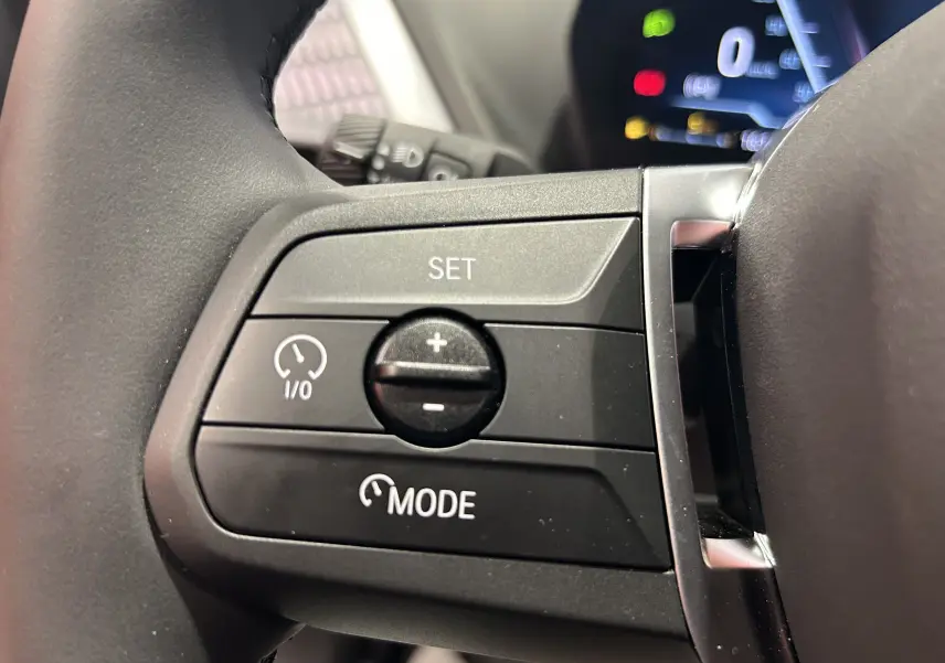 Gros plan sur les commandes de régulateur de vitesse au volant d'une BMW Série 1 120DA gris Skyscrap 2024.