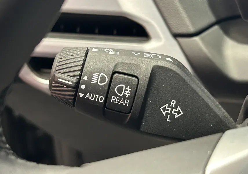 Gros plan sur la commande des phares et clignotants dans l'habitacle d'une BMW Série 1 gris Skyscrap 2024.