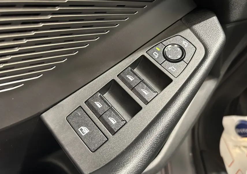 Gros plan sur les commandes des vitres et rétroviseurs côté conducteur de la BMW Série 1 120DA gris Skyscrap 2024.