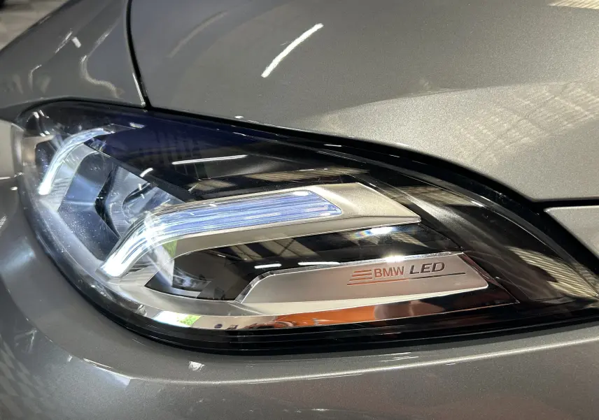 Gros plan sur le phare LED avant droit d'une BMW Série 1 gris Skyscrap avec détails chromés et inscription BMW LED.