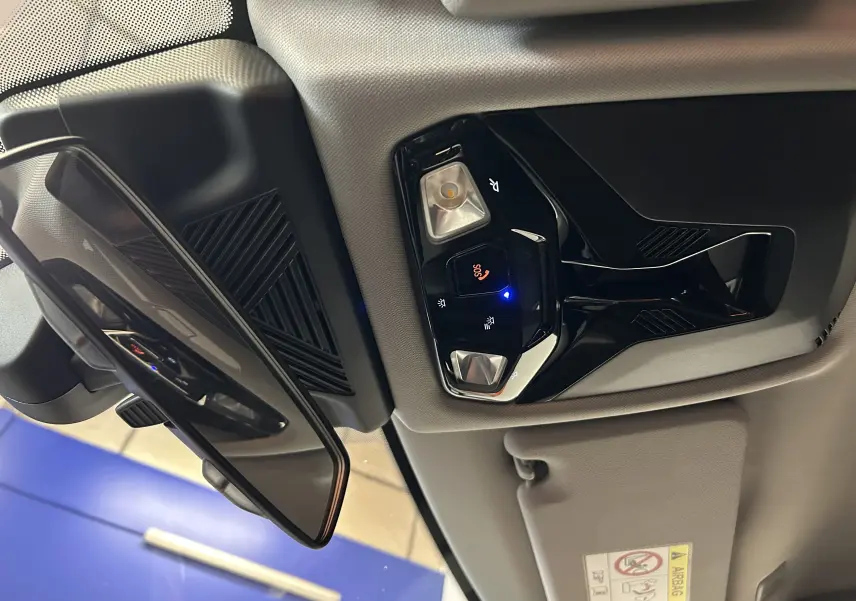 Vue intérieure du plafonnier et du rétroviseur d'une BMW Série 1 120DA 2024, avec commandes d'éclairage et bouton SOS.