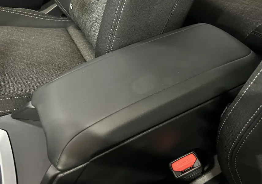 Accoudoir central en cuir noir et siège tissu gris foncé avec surpiqûres blanches dans une BMW Série 1 120DA 2024.