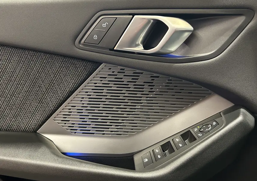 Poignée intérieure côté gauche de la BMW Série 1 120DA M Sport 2024 avec commandes de vitres et verrouillage, finition noire et grise.