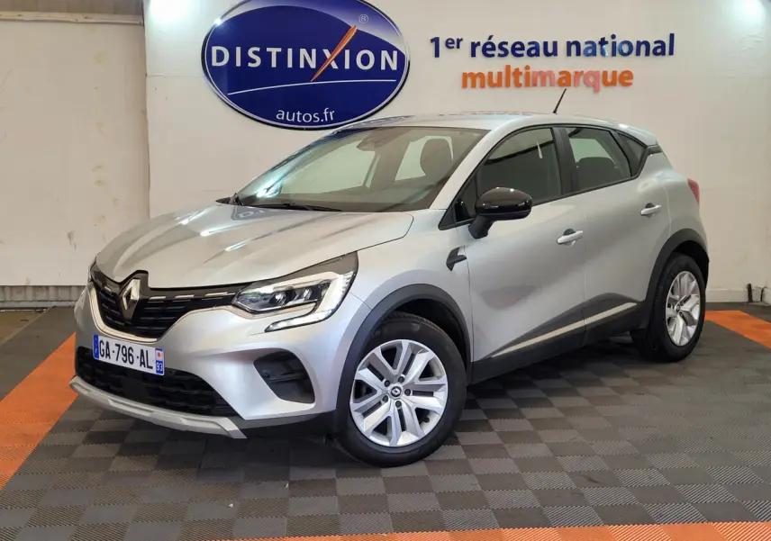 Renault Captur Business gris clair vu en 3/4 avant droit, avec jantes alliage et rétroviseurs noirs.