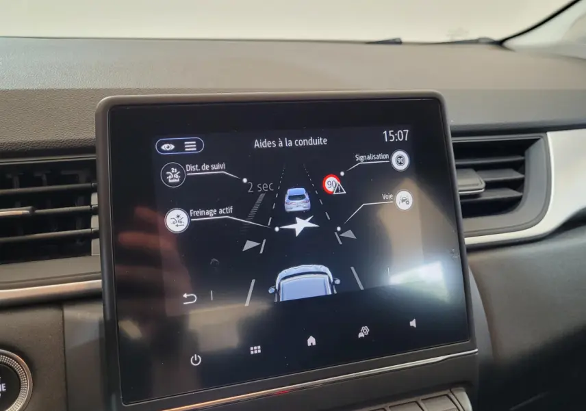 Écran tactile central du tableau de bord du Renault Captur Business gris clair montrant les aides à la conduite.
