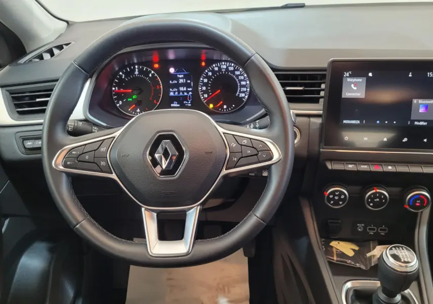 Vue intérieure frontale du tableau de bord du Renault Captur Business gris clair avec volant multifonctions et écran tactile.