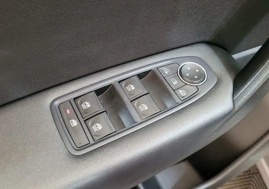 Gros plan sur les commandes de lève-vitres et rétroviseurs électriques côté conducteur du Renault Captur gris clair 2021.