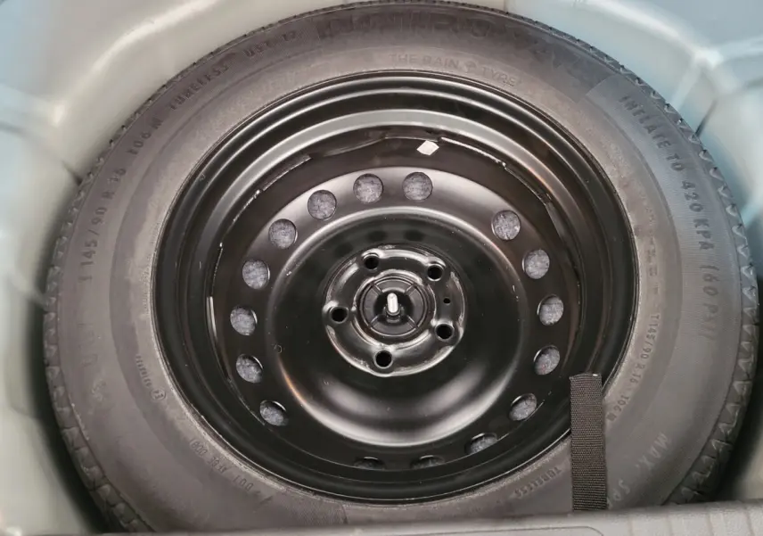 Gros plan sur la roue de secours noire dans le coffre d'un Renault Captur gris clair Business Blue dCi 95 2021.