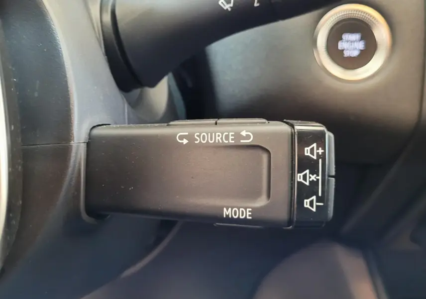 Gros plan sur la commande au volant du Renault Captur Business gris clair, avec bouton démarrage visible en arrière-plan.