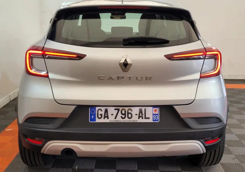 Vue arrière d'un Renault Captur Business Blue dCi 95 gris clair avec feux LED allumés dans un garage.