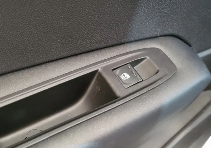 Gros plan sur le bouton de commande de la vitre électrique côté conducteur d'une Renault Captur gris clair 2021.