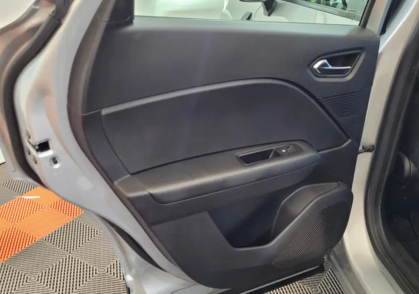 Porte arrière droite ouverte d'un Renault Captur gris clair, montrant le panneau intérieur noir avec commande de vitre.