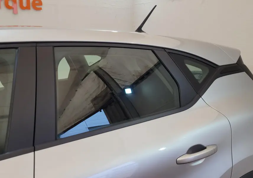 Vue latérale côté droit du Renault Captur Business gris clair, mettant en valeur la porte arrière et la lunette teintée.