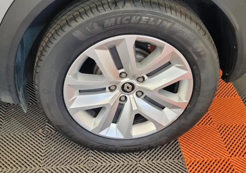 Gros plan sur la roue avant droite d'un Renault Captur gris clair, jante alliage et pneu Michelin visible.