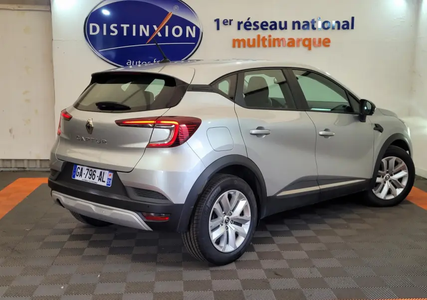 Vue 3/4 arrière droite d'un Renault Captur gris clair 2021 avec feux LED et jantes alliage en showroom.