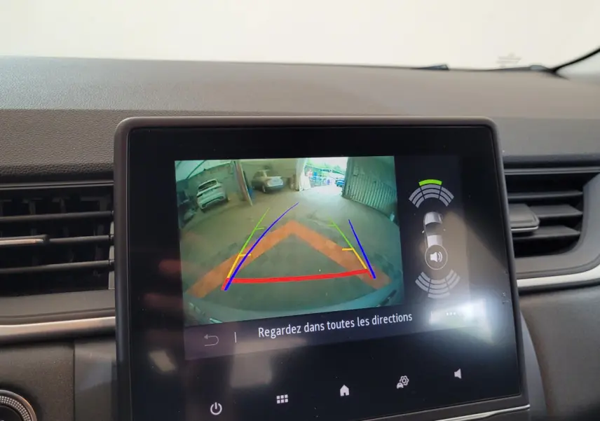 Écran tactile intérieur montrant la caméra de recul et l'aide au stationnement du Renault Captur gris clair 2021.