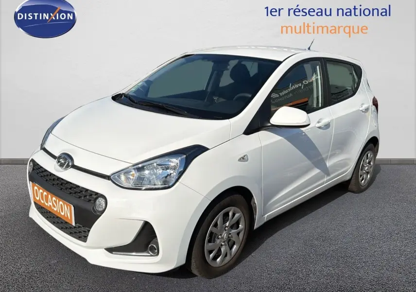 Vue 3/4 avant droite d'une Hyundai i10 blanche de 2018 avec calandre noire et jantes alliage.
