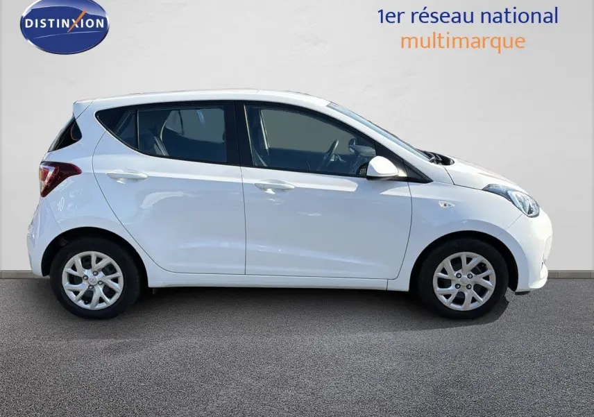 Profil latéral droit d'une Hyundai i10 blanche de 2018, compacte et cinq portes, sur fond neutre.