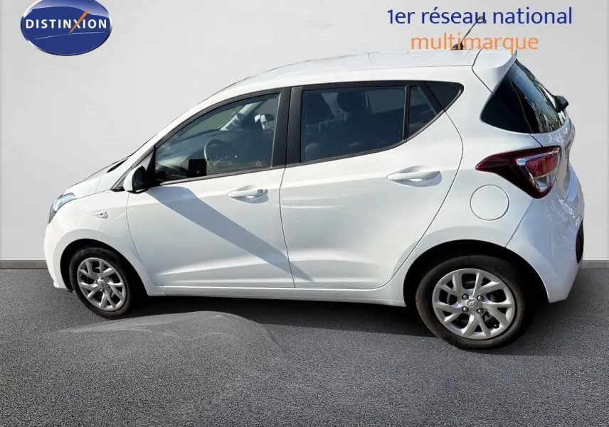 Profil côté gauche d'une Hyundai i10 blanche 2018, compacte cinq portes avec jantes alliage et vitres teintées.