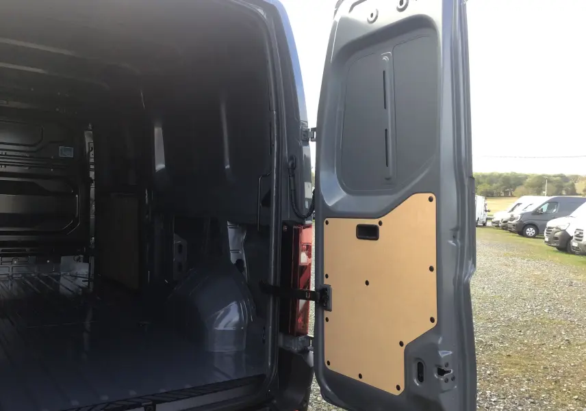 Vue arrière ouverte du Renault Master gris urbain, montrant l'intérieur vide et la porte arrière avec panneau de protection beige.