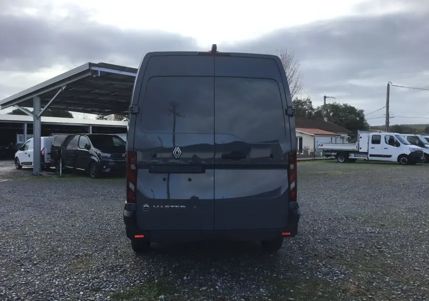 Vue arrière d’un Renault Master L3H2 gris urbain 2025, avec portes arrière fermées sur un sol gravillonné.