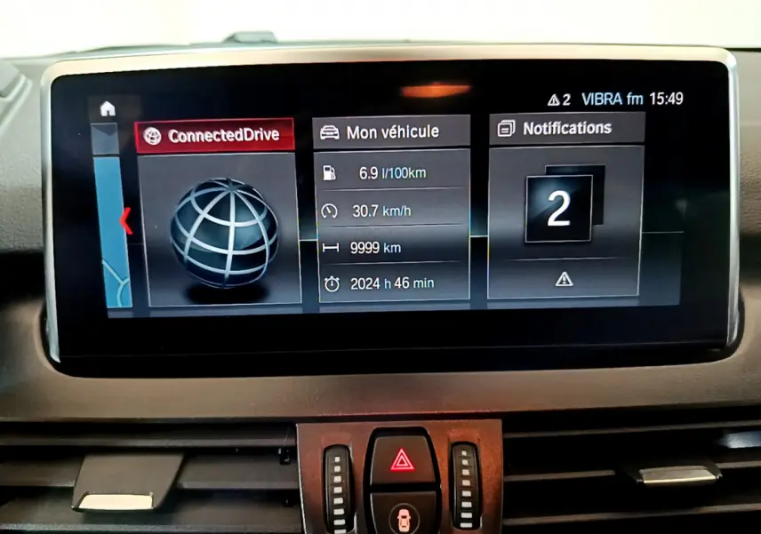 Écran central du tableau de bord de BMW Série 2 Gran Tourer 218d gris clair, affichage connecté et informations véhicule.