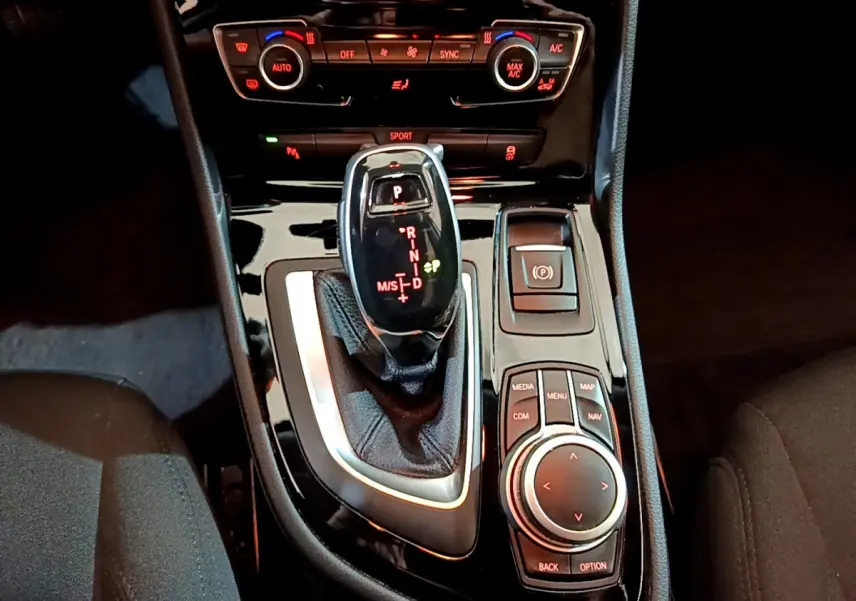 Vue rapprochée du levier de vitesses automatique et des commandes centrales noires de la BMW Série 2 Gran Tourer gris clair.